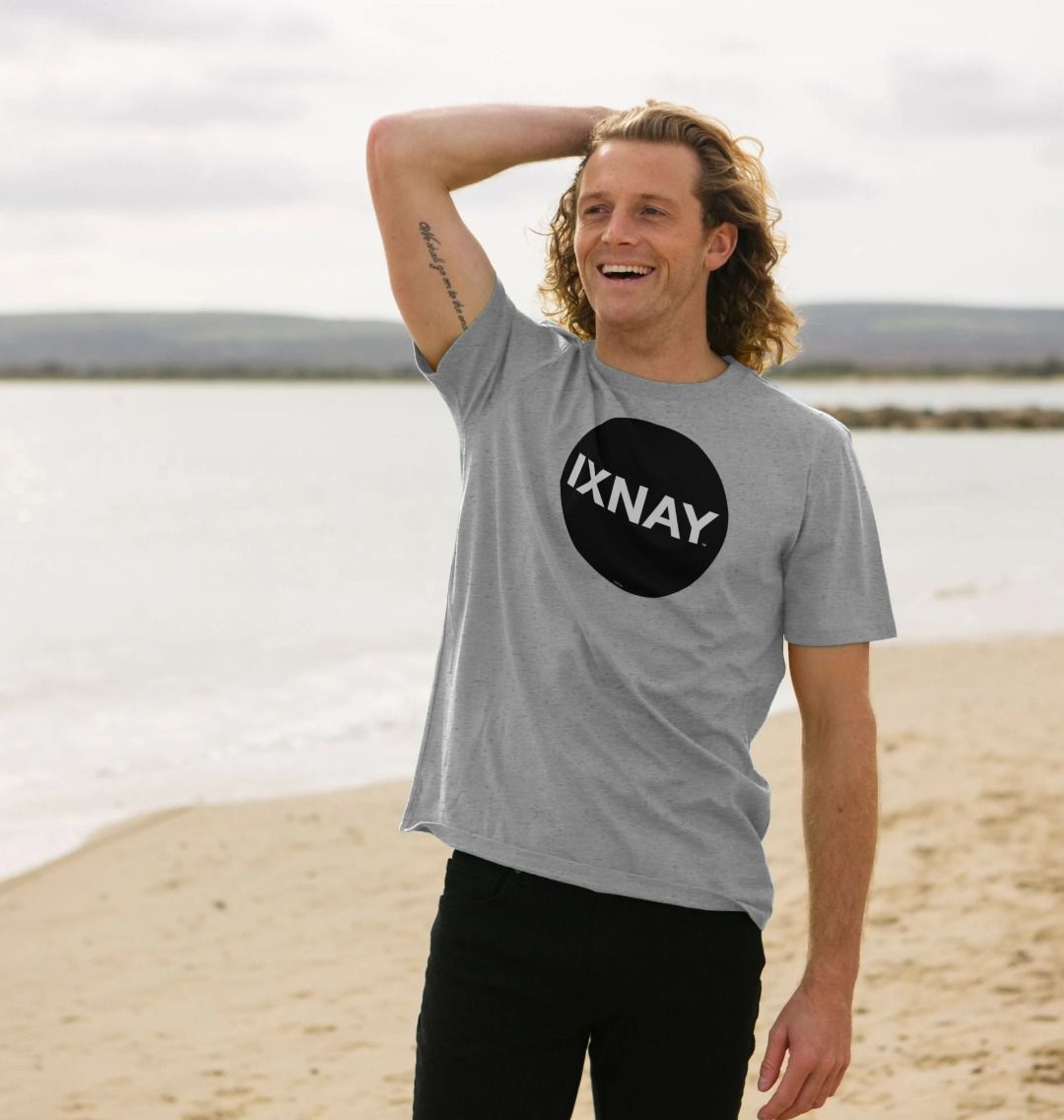 Man smiling and laughing in awe of the beach while wearing a light gray Printed Men's T-Shirt with Original Black Round IXNAY Logo to represent the artist and musician IXNAY