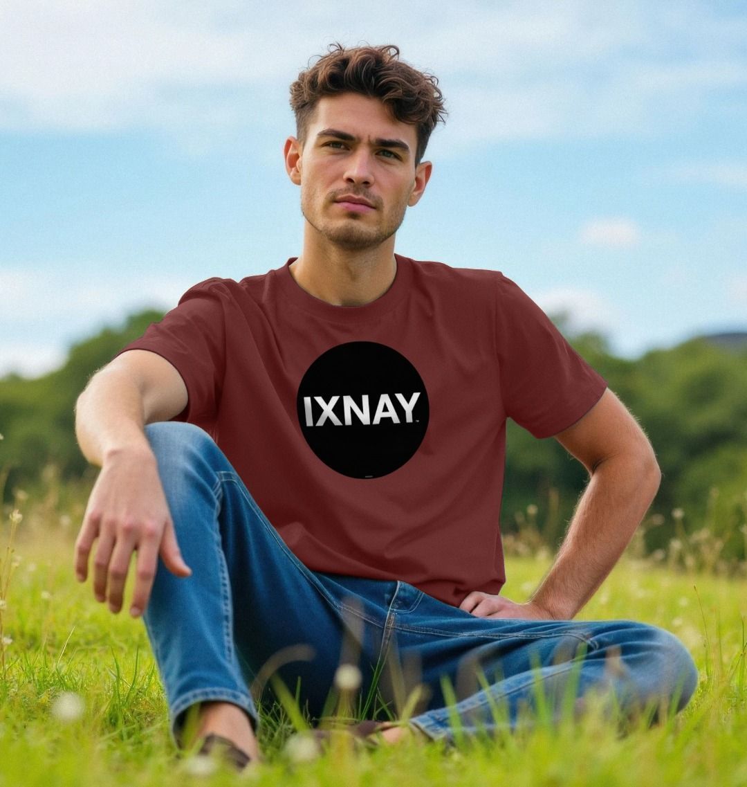 Man sitting in the grass of a large meadow wearing a wine red Printed Men's T-Shirt with Original Black Round IXNAY Logo to represent the artist and musician IXNAY