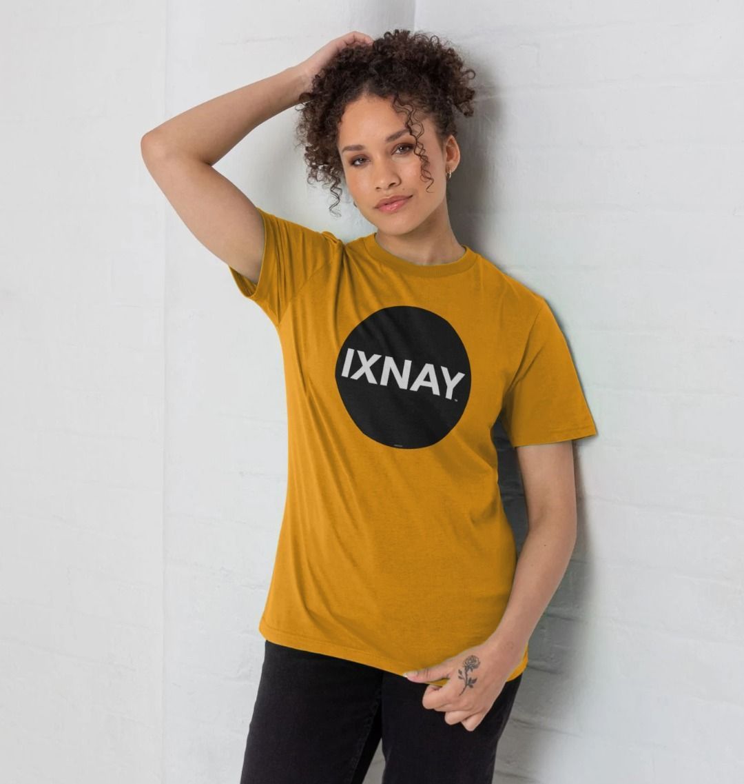 Woman smiling during a photoshoot with an all white backdrop wearing a mustard yellow Printed Men's T-Shirt with Original Black Round IXNAY Logo to represent the artist and musician IXNAY