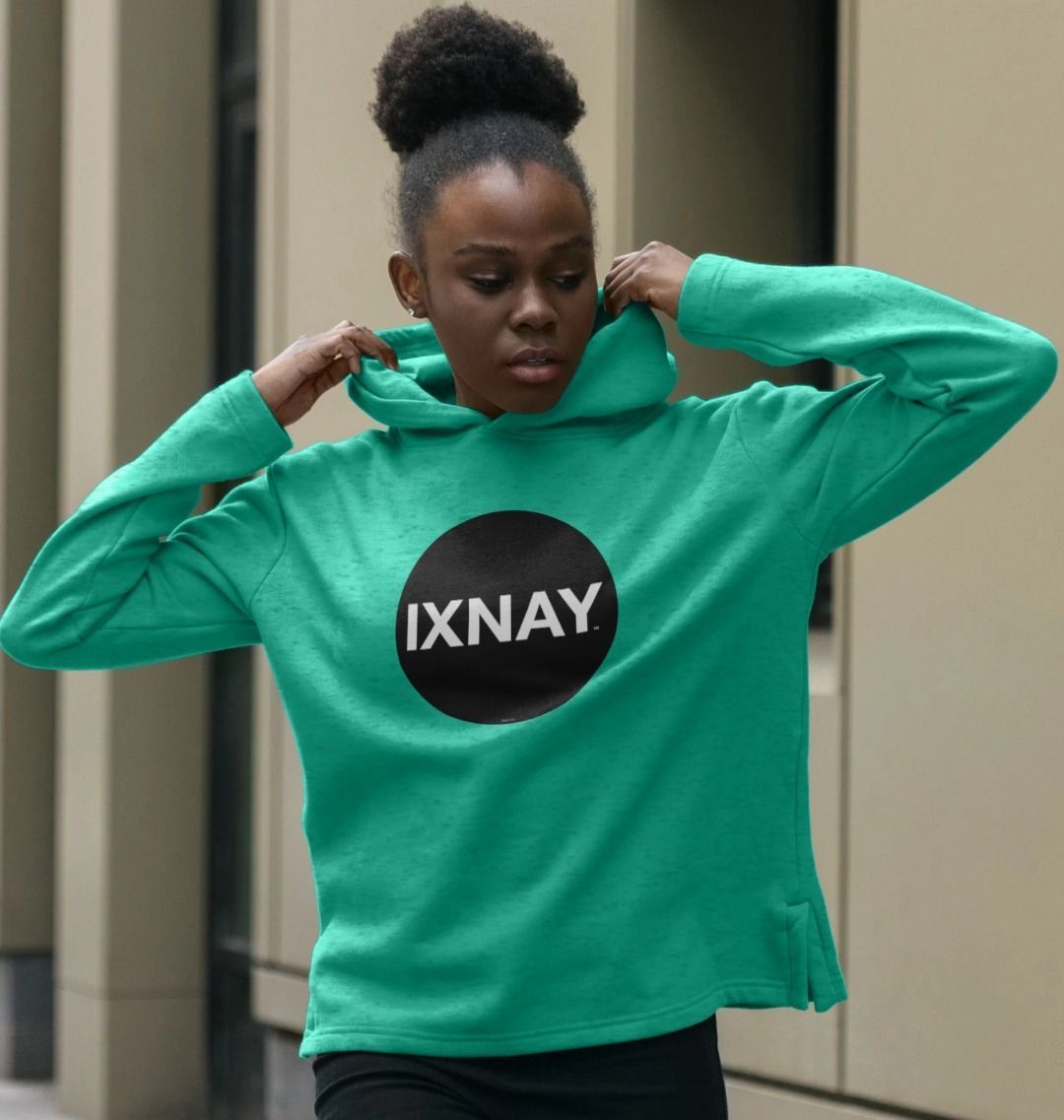 black woman wearing womens seagrass green organic remill pullover hoodie with original black round IXNAY logo